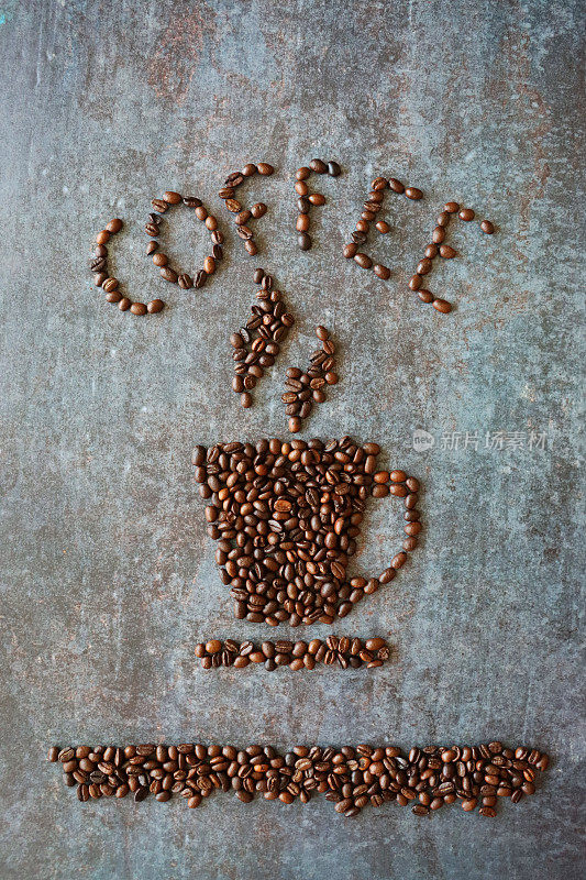 在一个杯子和茶碟上，用整颗咖啡豆写着“咖啡”这个词，杯子和茶碟上的蒸汽设计是由一堆烤好的咖啡豆在斑驳的、灰色的背景上形成的