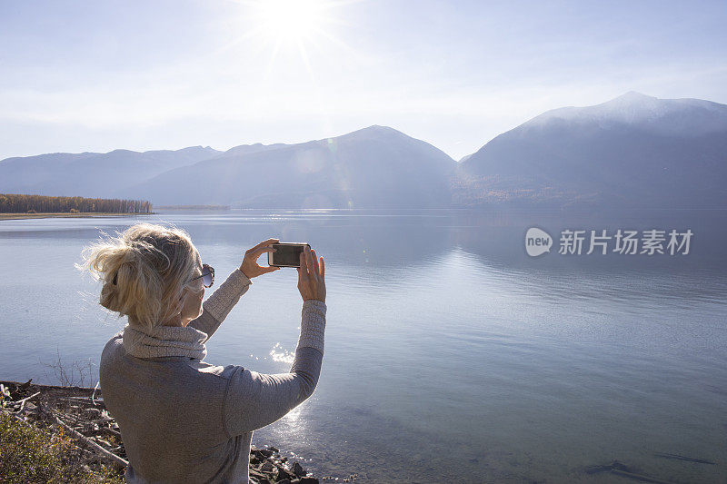 一名女子在山间湖泊上使用智能手机