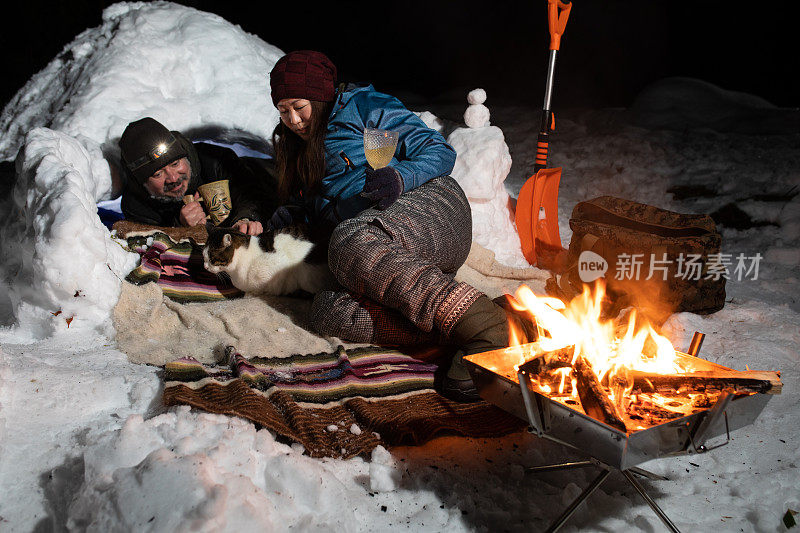 一对夫妇和他们的宠物猫在他们的雪帐篷里休息