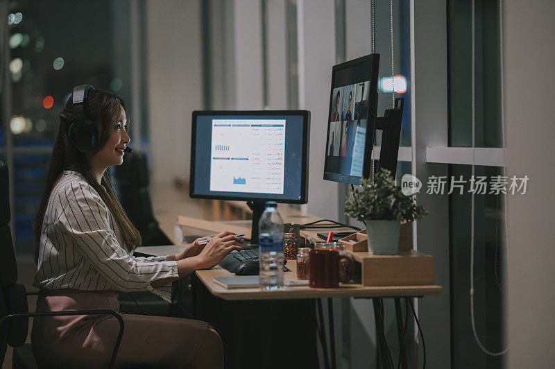 亚洲华人女性白领视频电话工作到很晚，在办公室里独自在低光