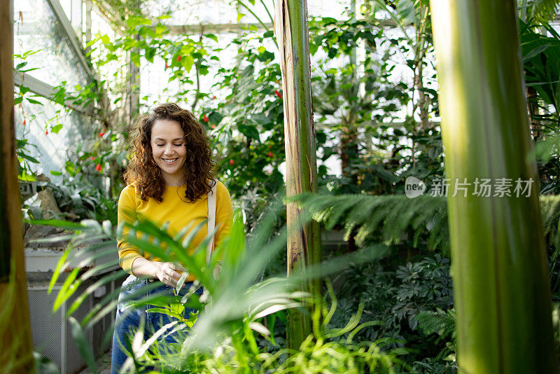 一个年轻的白人妇女在植物园里玩得很开心