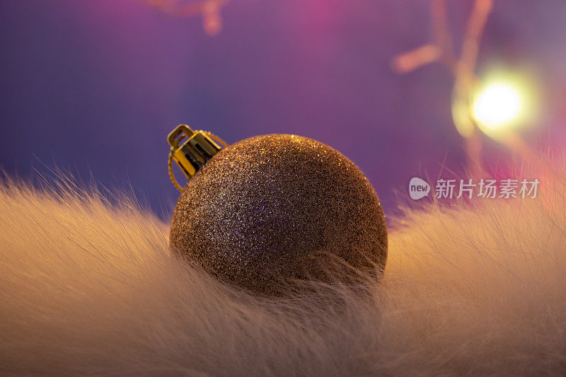 在紫色和粉红色的背景上的金色球圣诞装饰。圣诞节灯泡。