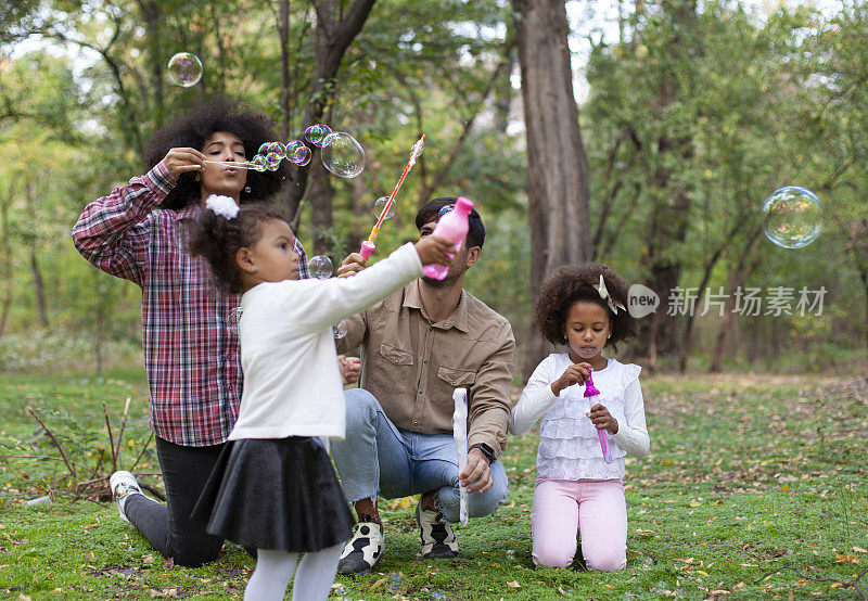 快乐的一家人在公园里玩肥皂泡。