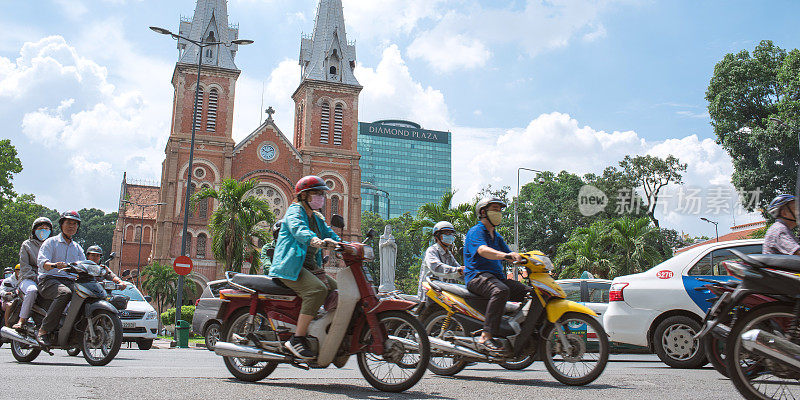 人们骑着摩托车和越南西贡圣母院大教堂