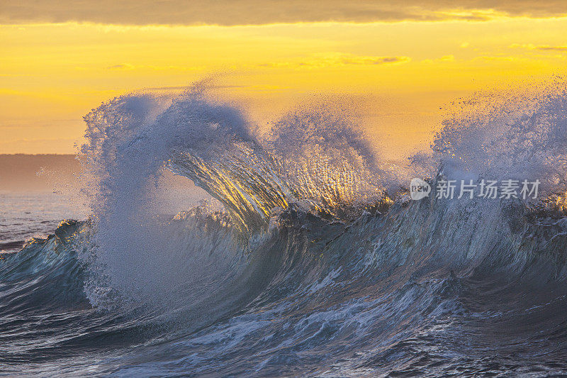 狂暴的海浪危险地打破，被明亮的金色晨光照亮