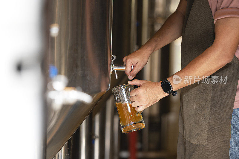 一个年轻人在啤酒厂工作，检查精酿啤酒的质量。酿酒厂老板品尝到巴赫最好的啤酒。男人的捷径能装满一杯啤酒