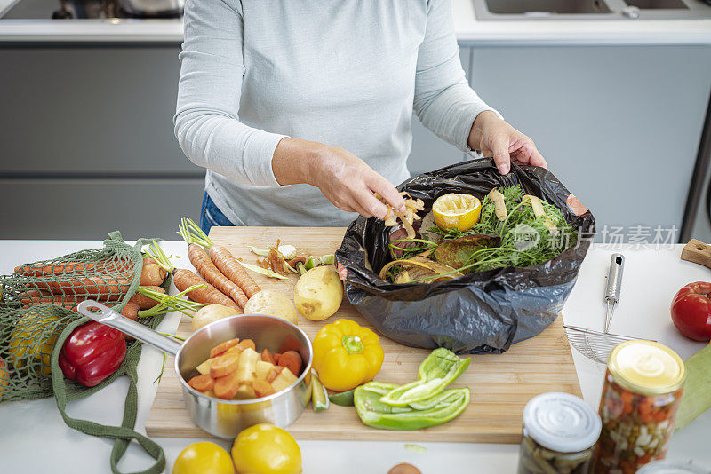 妇女回收蔬菜皮在一个垃圾袋