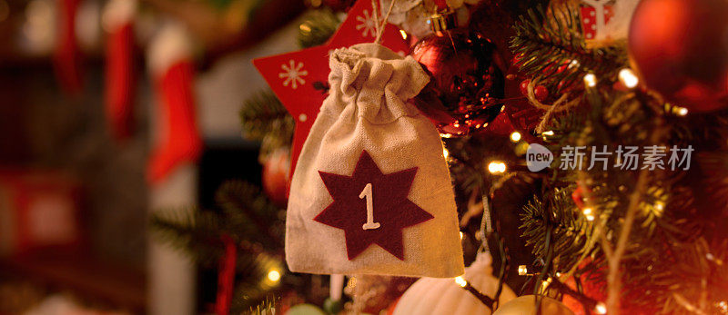 以生态袋的形式出现的日历挂在圣诞树上，背景是有壁炉和圣诞老人的靴子的圣诞屋。圣诞节的背景。出现日历。
