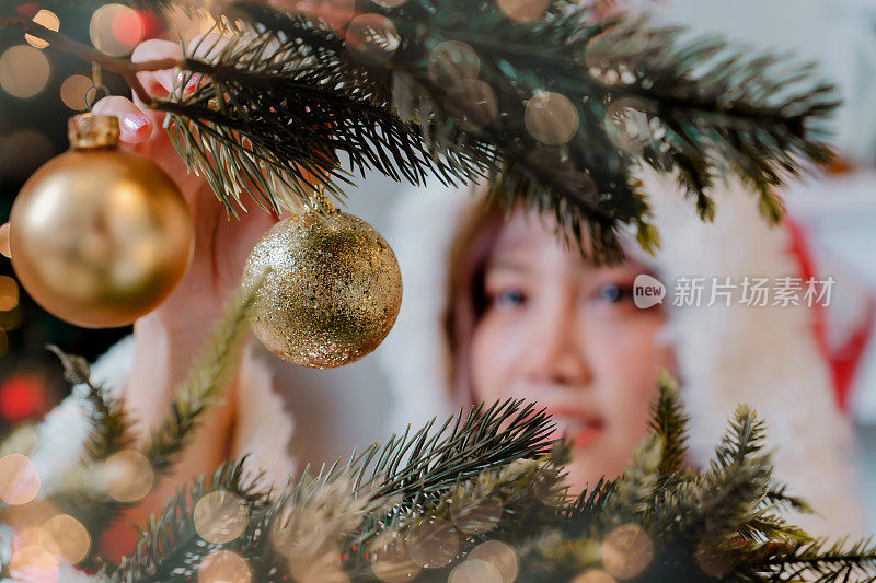寒假在家举行圣诞晚会。亚洲妇女装饰圣诞树。
