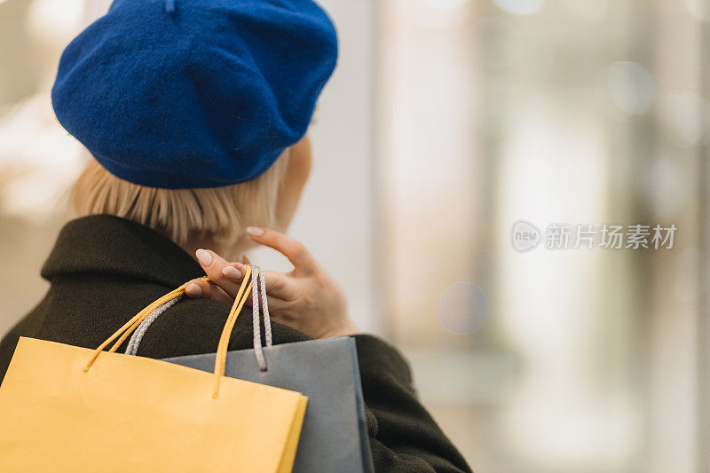 戴贝雷帽的金发女人，手里拿着购物袋