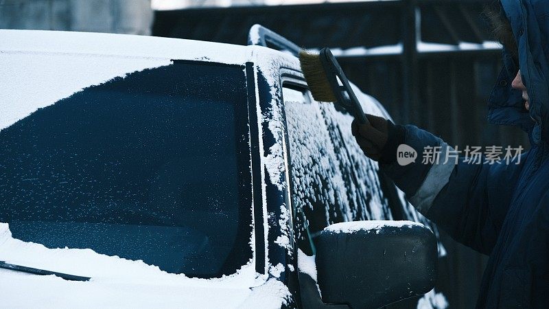 降雪后，一名妇女正在清洗家用汽车