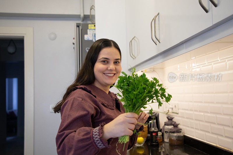 年轻女子在厨房做饭，她面前放着欧芹