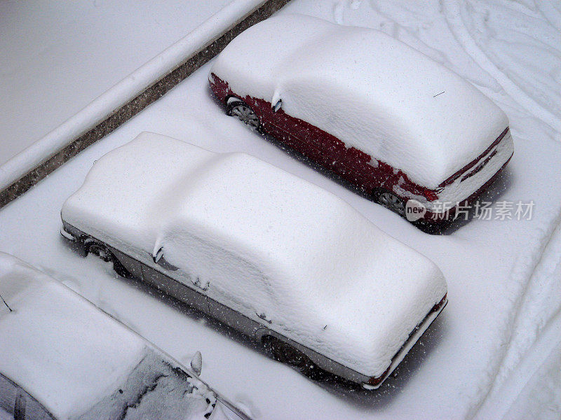 公寓停车场三辆车被雪覆盖的侧面视图