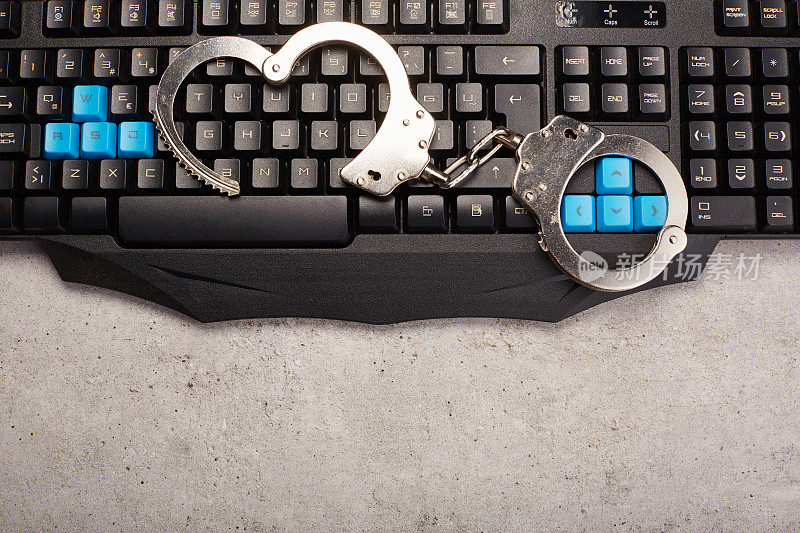 电脑键盘上的金属手铐，网络犯罪