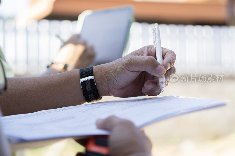 检查现场时，工人用钢笔在纸上写字的近距离手。