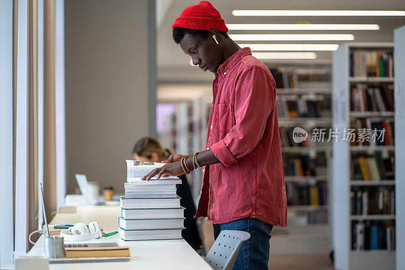 非裔美国学生站在图书馆寻找论文资源