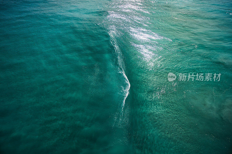 正上方的鸟瞰图，海浪在海滩碧蓝的海水中破碎