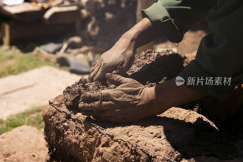 一个人用他的手用土砖和泥盖了一座土坯房。秘鲁的的喀喀湖的拉孔地区。