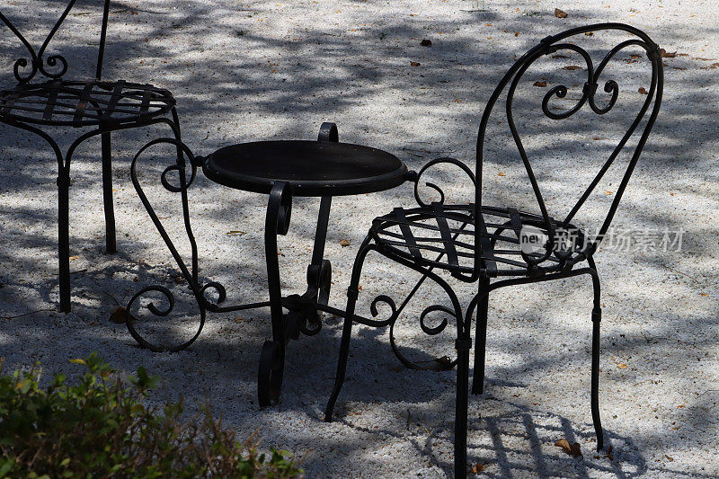 图像的黑色油漆，圆形锻铁，金属花园庭院桌椅，沥青露天用餐区，重点在前景