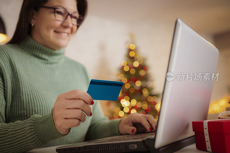 成熟女人用笔记本电脑用信用卡买圣诞礼物