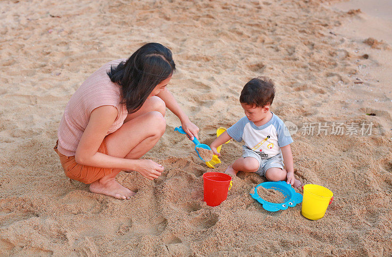 幸福美满的家庭。妈妈和儿子在沙滩上用塑料玩具玩沙子。