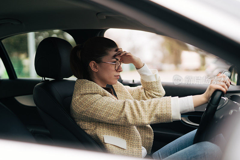 愤怒的年轻女子开着车，被拥挤的交通弄得心烦意乱。侧视图。