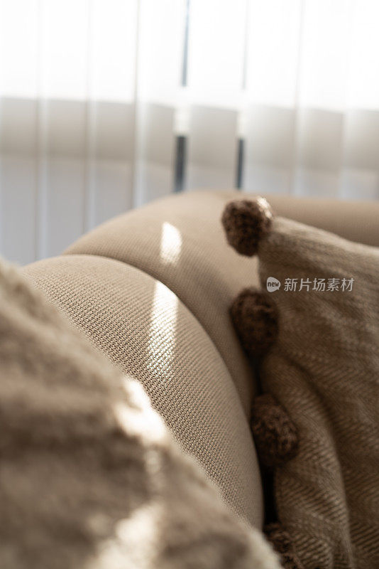 阳光透过窗帘照射在米色现代生活空间的沙发上