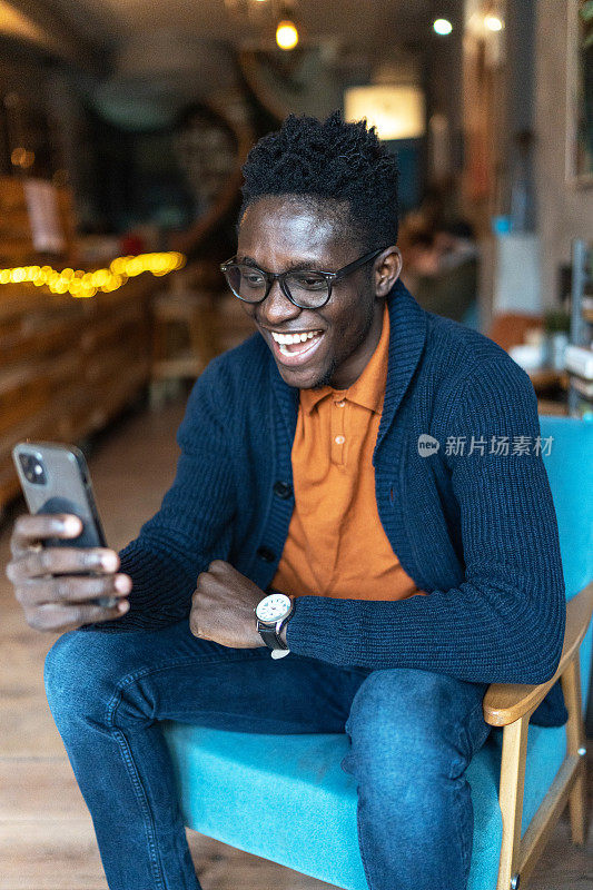 开朗的黑人在咖啡店使用智能手机