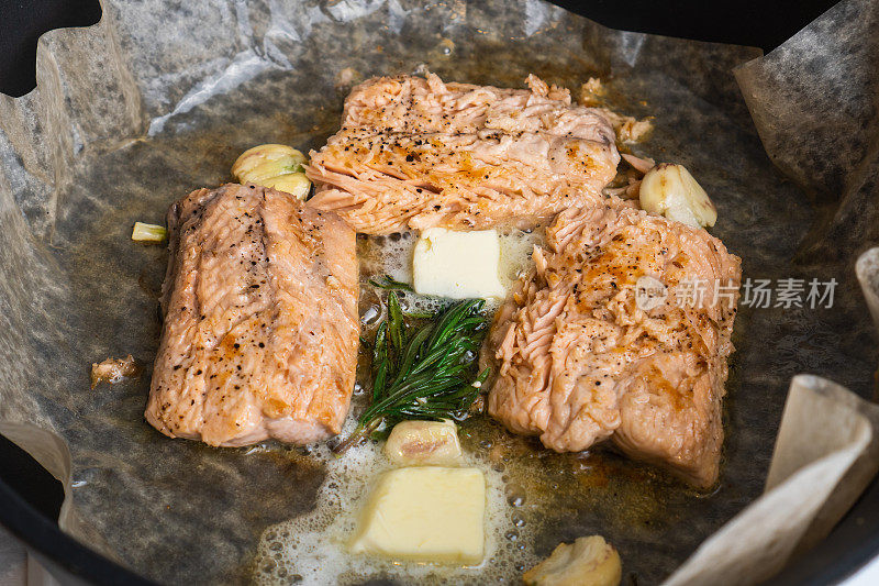 三文鱼排在烤盘纸上与香草和大蒜一起烹饪。红鱼肉制作
