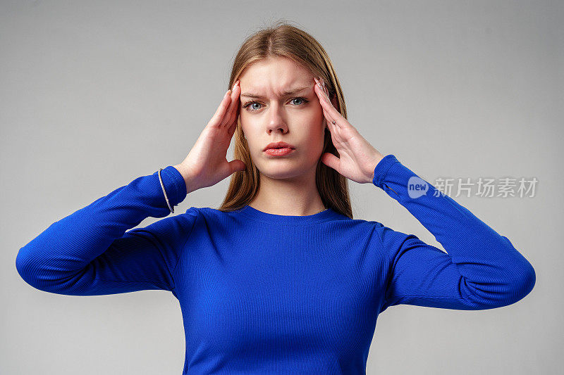 穿蓝上衣的女人在演播室里双手对着耳朵