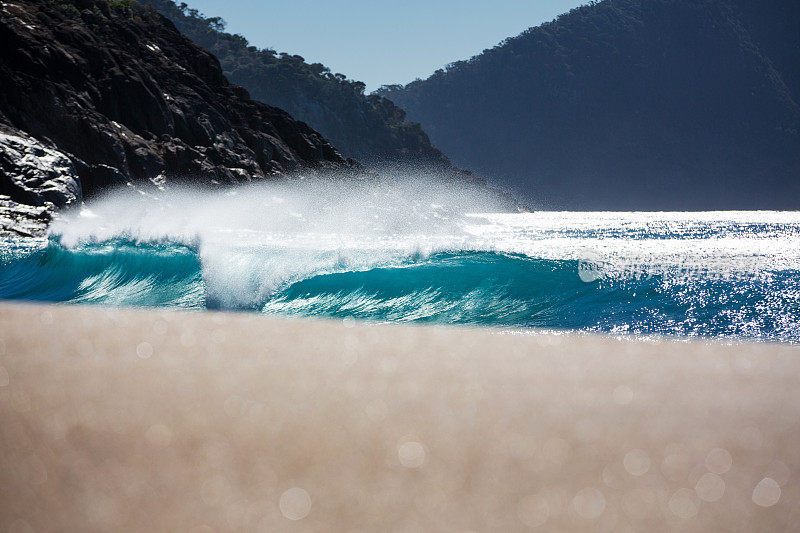 一个完美的水色波浪沿着沙滩海岸线破碎的沙滩视图