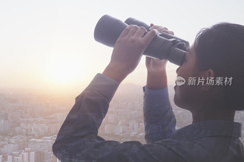 年轻的女商人拿着双筒望远镜俯瞰北京