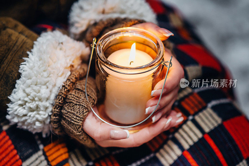 女人的双手在温暖的冬天紧紧地握着燃烧的蜡烛