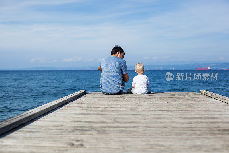 父亲和儿子坐在码头上