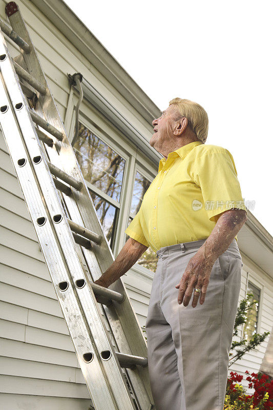 一个老人在考虑靠在房子上的梯子