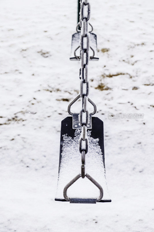 操场上的秋千在暴风雪中被雪覆盖