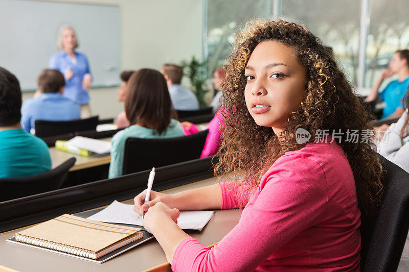 年轻的女大学生在课堂上做笔记