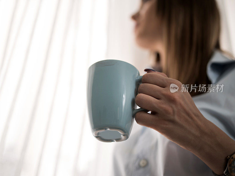 一个女人拿着咖啡杯的特写。