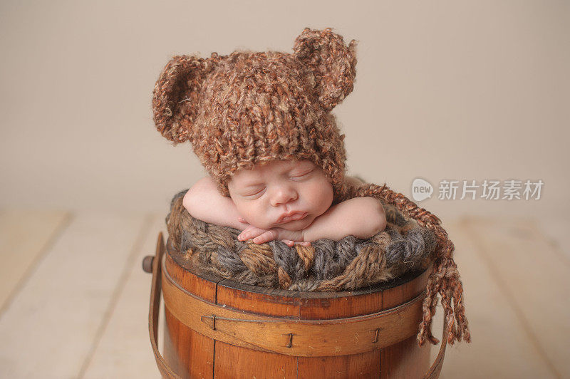 新生儿戴着针织帽睡在桶里的特写