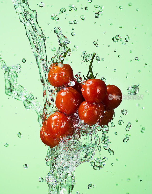 水泼在樱桃番茄上。绿色背景