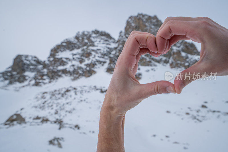 人的双手在雪山景观上做出心形