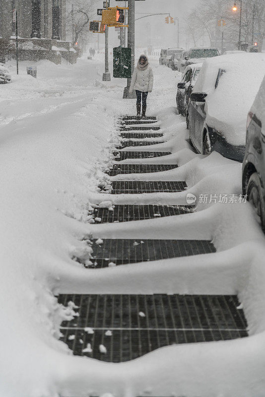 少女走在曼哈顿的街道上的雪下