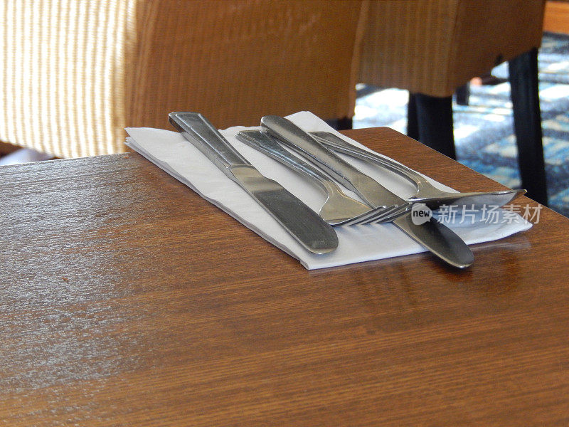 木桌上的餐具，勺子，刀叉，白色餐巾