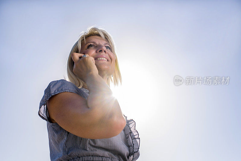 对着天空，电话里微笑的女商人。