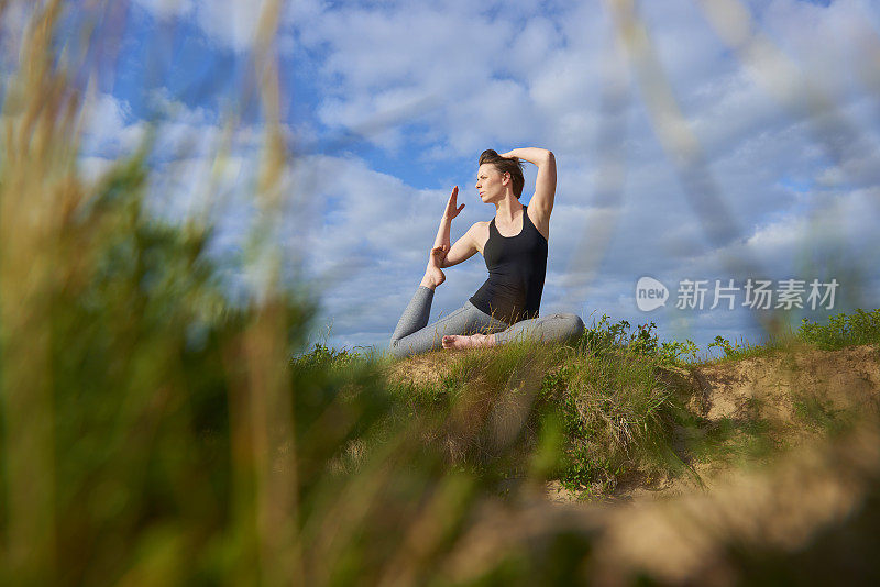 一个年轻女子在室外的一些植物后面做瑜伽