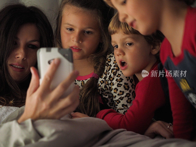母亲在床上与孩子分享智能手机