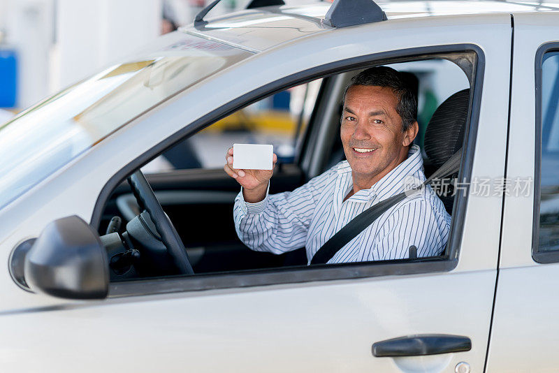 一个人在加油站开车，手里拿着会员卡