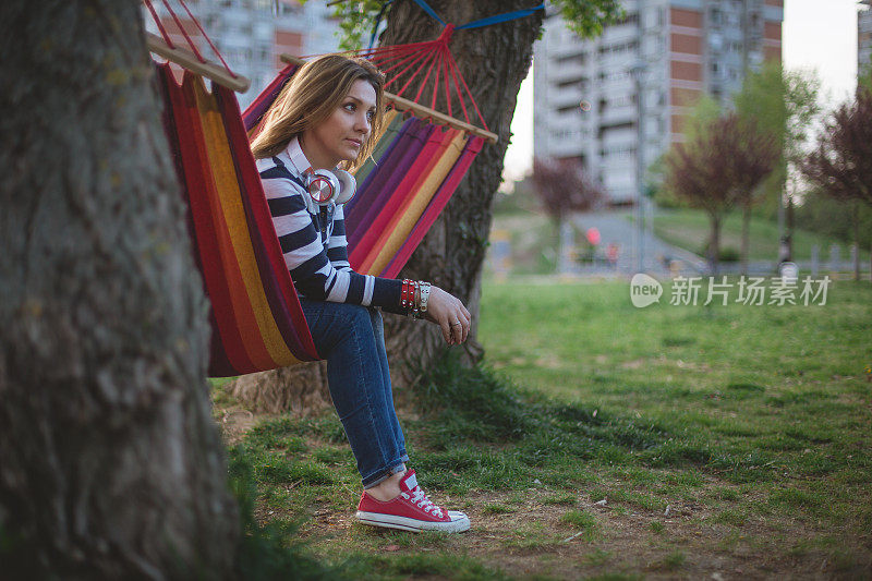 一个女人坐在公园的吊床上思考