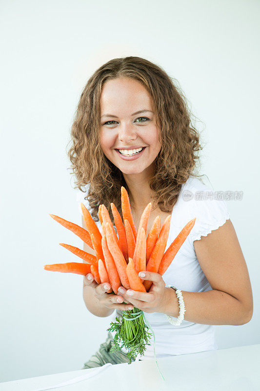 饮食系列:手持胡萝卜的年轻女子