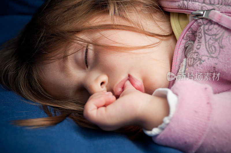 熟睡中的女婴吮着她的拇指